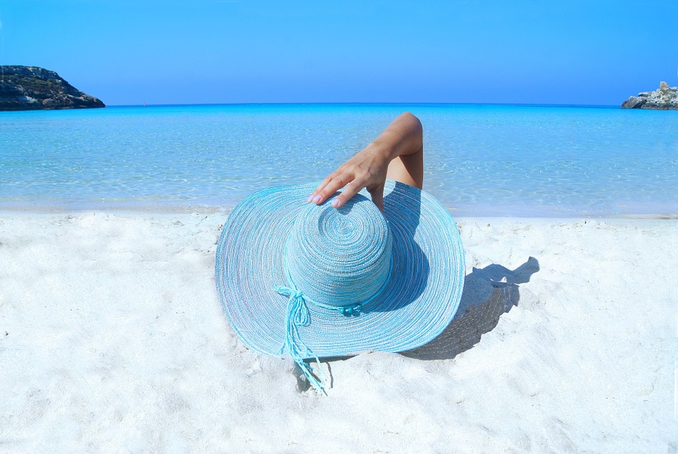 persona tomando el sol en la playa con un sombrero