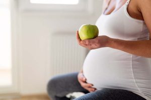 mujer embarazada sujetando una manzana