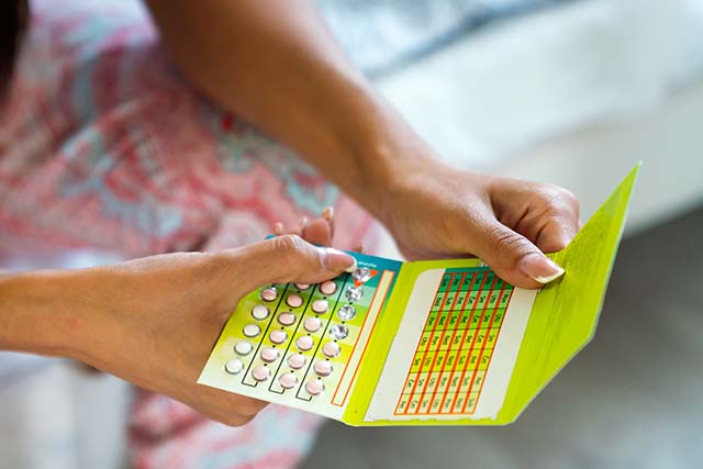mujer con un blister de píldoras anticonceptivas en la mano