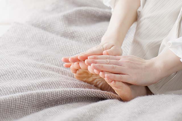 persona con sabañones tocándose los pies